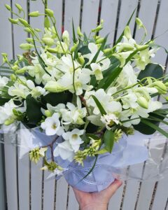 short vase filled with white orchids freesias and white daphne flowers